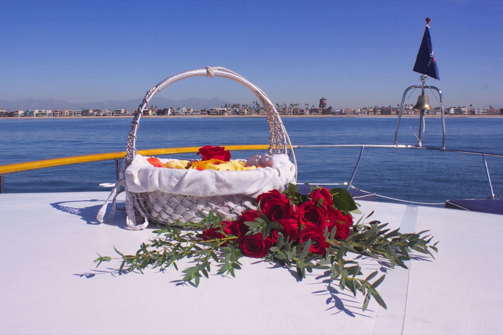 A prepared basket with red roses and the ship's bell, resting on the bow